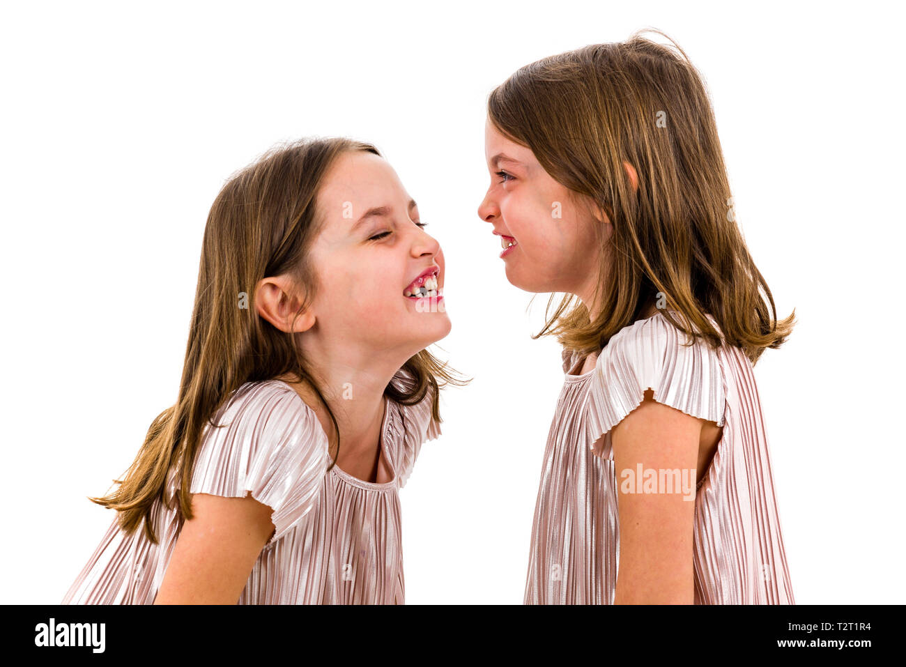 Zwilling Mädchen sind sich einander und lächelnd. Konzept der Familie und schwesterliche Liebe. Profil Seitenansicht des Twin sisters in den Kleidern suchen Stockfoto