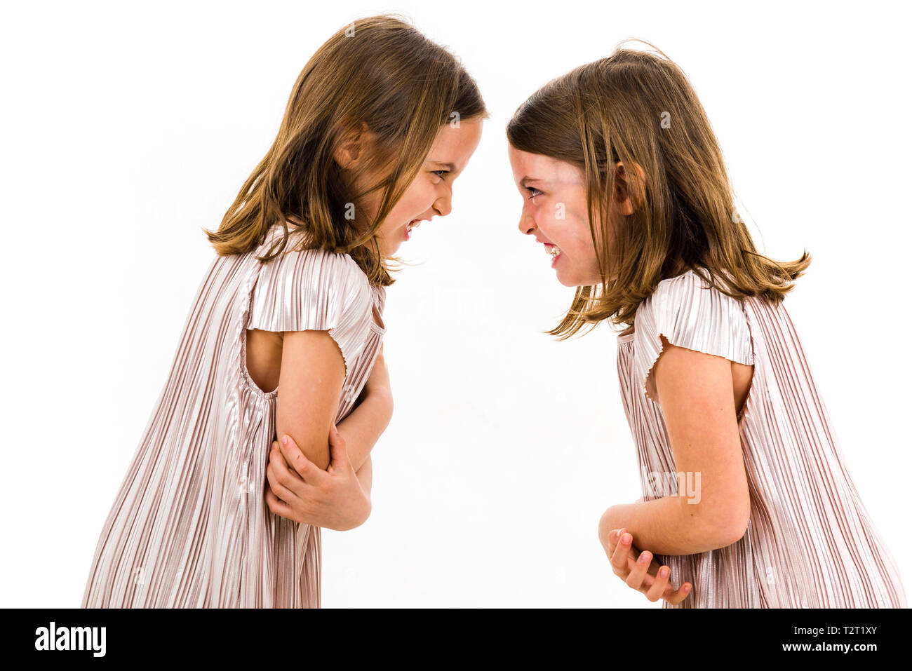 Identische Zwillinge Schwestern streiten sich gegenseitig zu beschimpfen. Böse Mädchen schreien, kreischen und argumentieren mit den emotionalen Ausdruck auf den Gesichtern. Fron Stockfoto