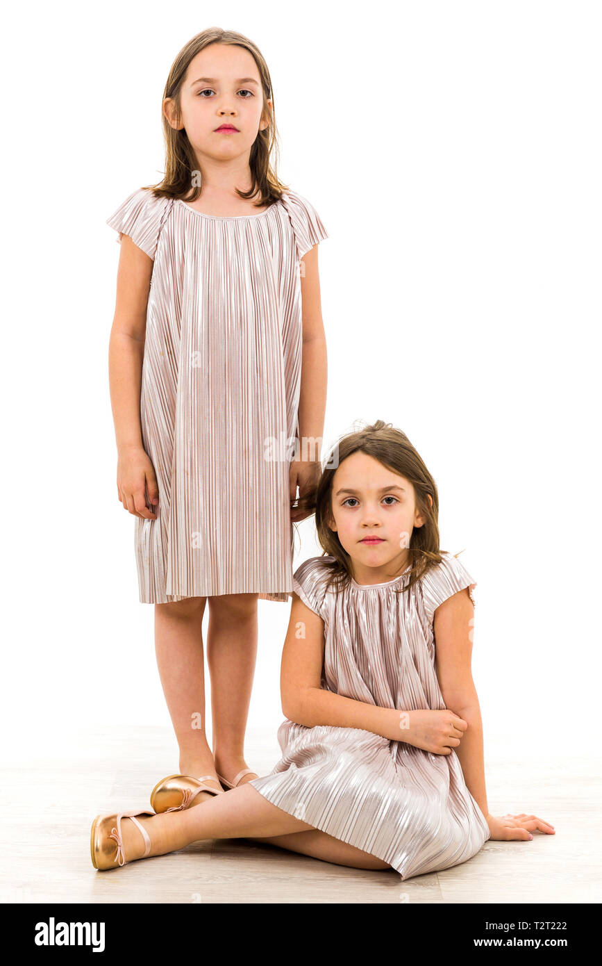 Identische Zwillinge Schwestern sind posieren für die Kamera. Zwillingsschwestern in Kleider betrachten die Kamera mit traurig, langweilig. Vorderansicht, Studio Stockfoto
