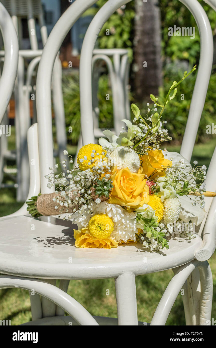 Farbenfrohe wedding bouquet mit gelben Rosen, Chrysanthemen und Sun Flowers Festlegung auf einem weißen Holzstuhl. Tropische Hochzeit. Stockfoto