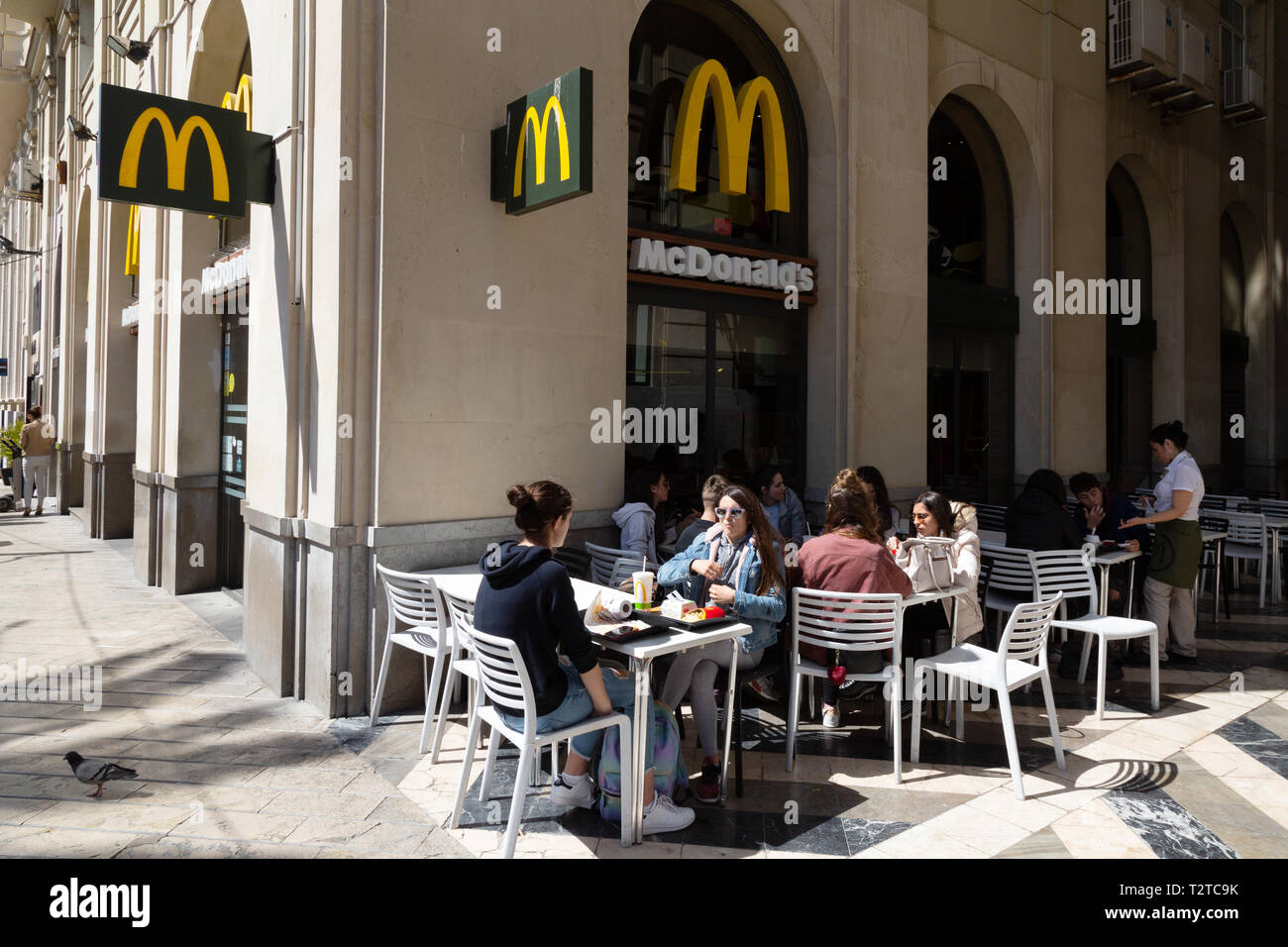 McDonalds Spanien - Leute, die Essen und Trinken außerhalb des McDonalds Fast Food Restaurant, Malaga, Andalusien Spanien Europa Stockfoto
