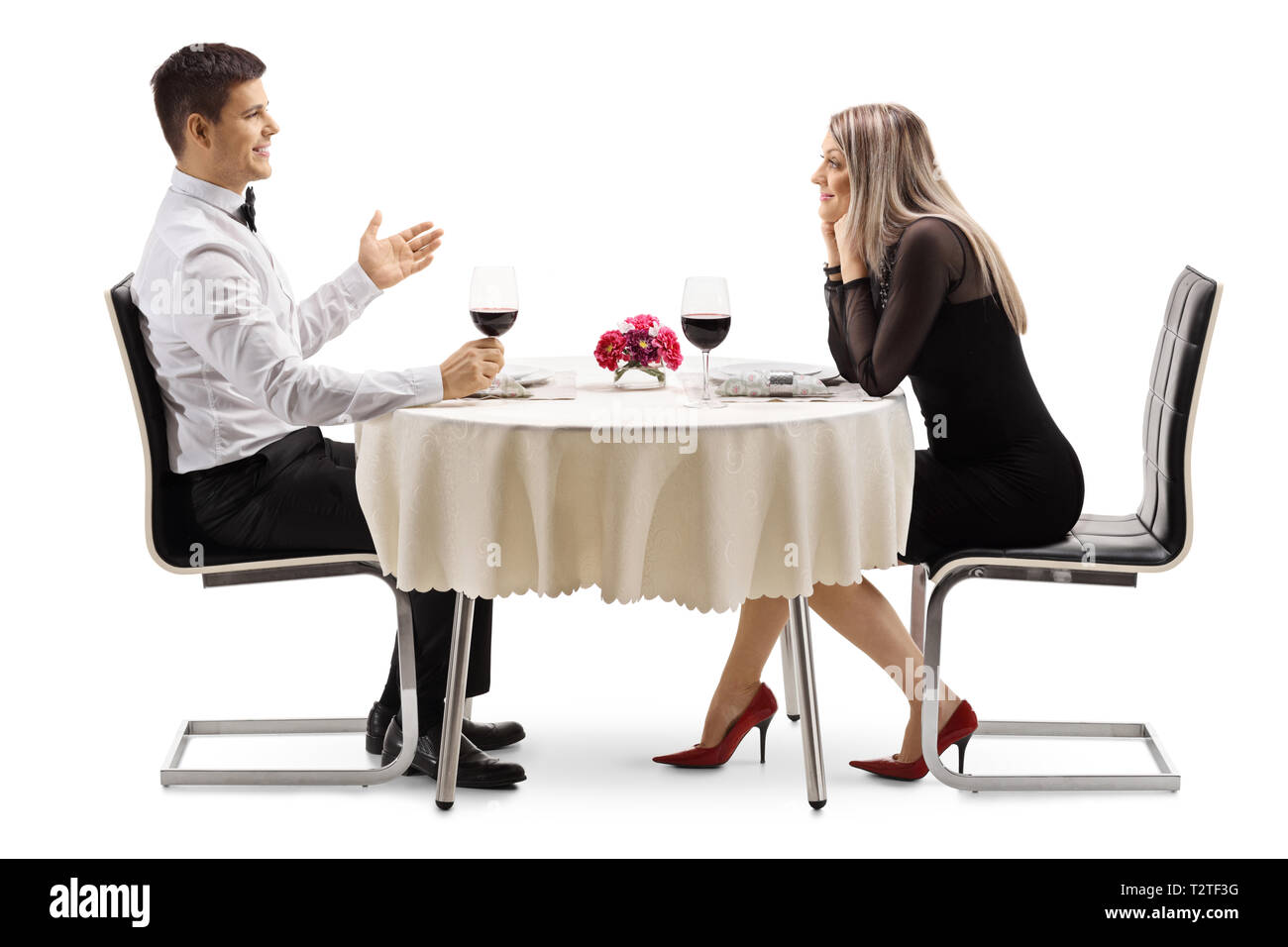 Volle Länge Profil Schoß eines jungen Mannes mit einer jungen Frau an einem Tisch im Restaurant auf weißem Hintergrund Stockfoto