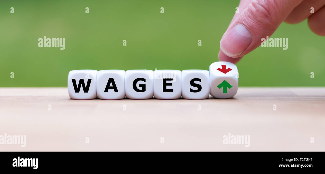 Symbol für eine Gehaltserhöhung. Hand verwandelt einen Würfel und verändert die Richtung, in die sich ein Pfeil von unten nach oben. Würfel form Löhne das Wort''. Stockfoto