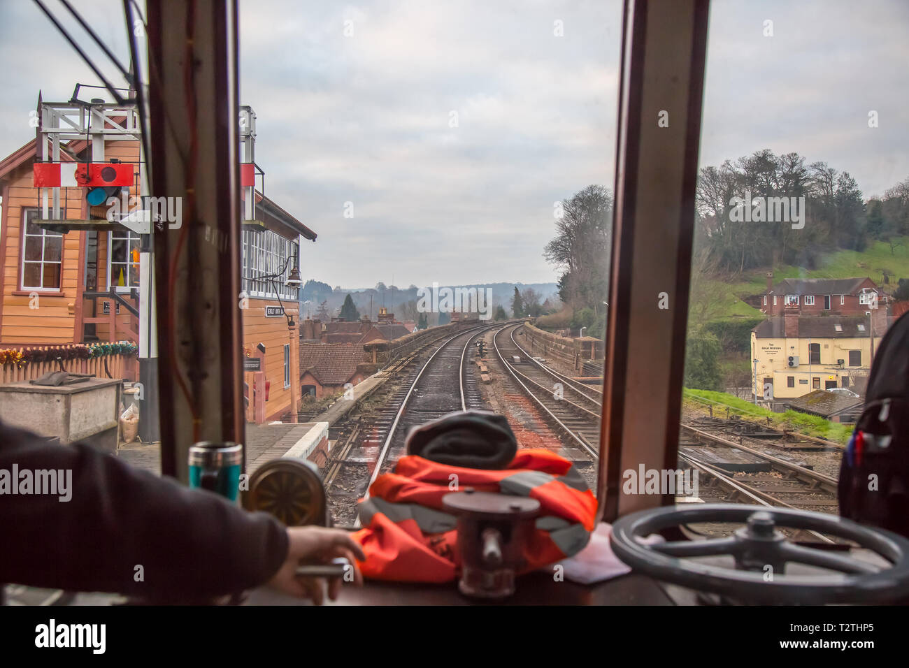 An der Steuerung: Blick des Zugfahrers durch die Frontscheibe des fahrenden Dieselzugs auf der historischen Eisenbahnlinie. Verlassen der Vintage Station. Stockfoto