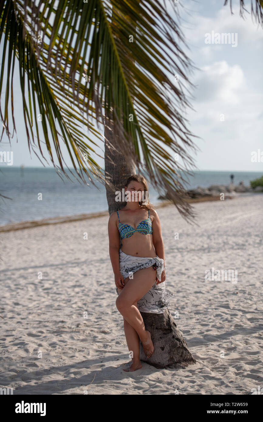 Junge Frau mit Bikini hängen auf der Palme auf der Sandstrand in USA Stockfoto