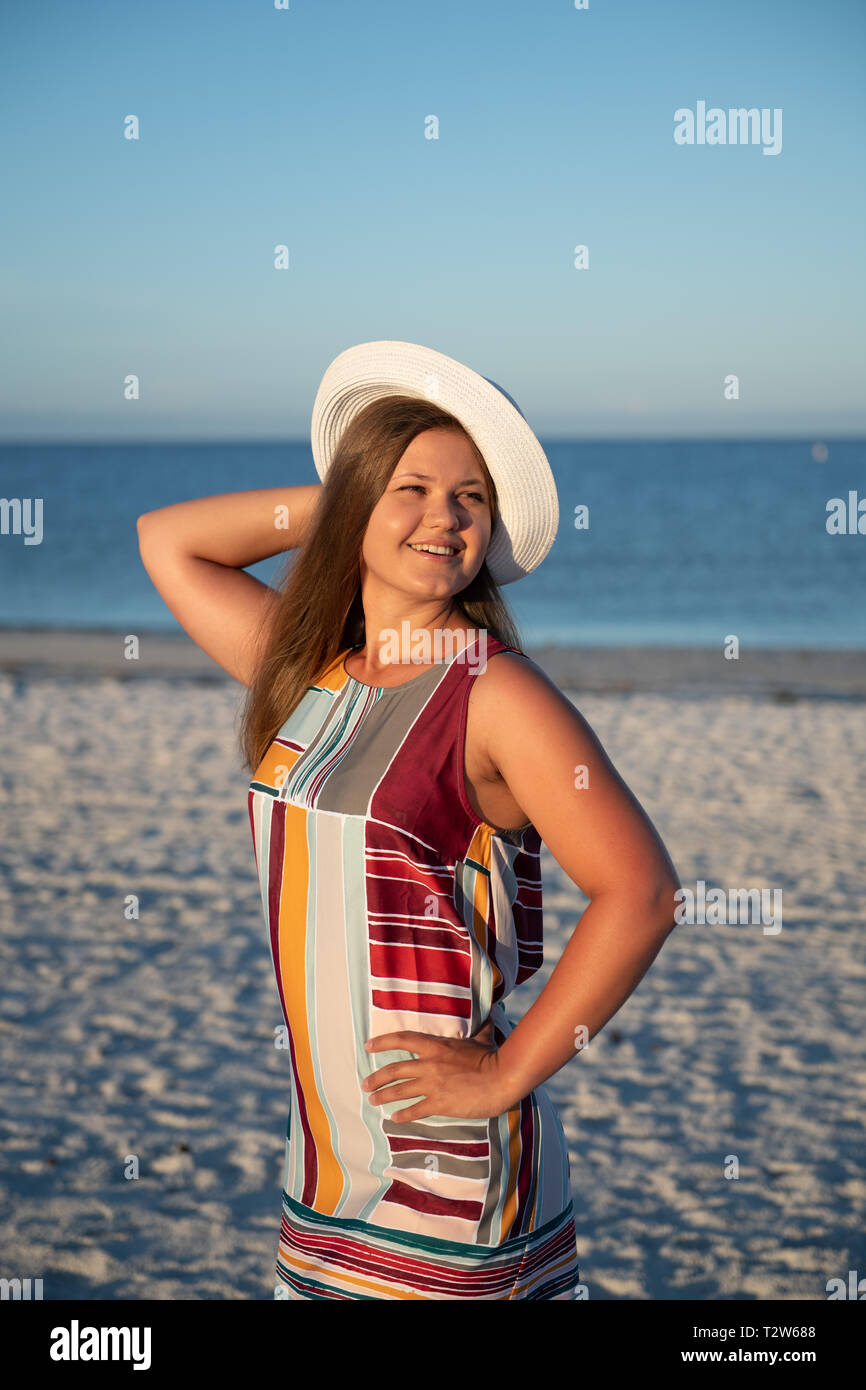 Portrait einer jungen schönen Frau sorglos wandern an sonnigen Strand tragen kleid und hut Stockfoto