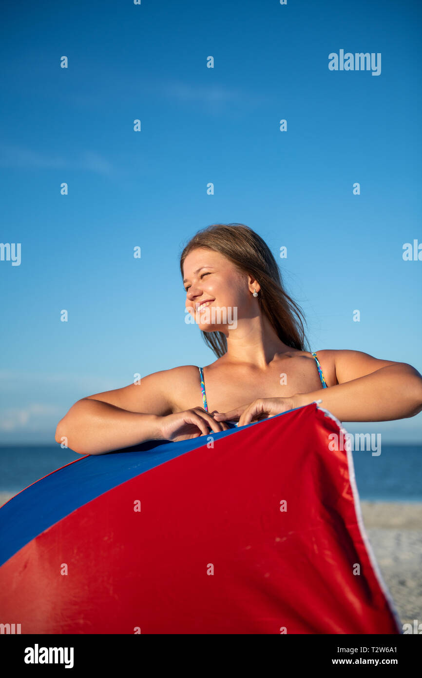 Glückliche Frau im Bikini am Strand mit Schirm Stockfoto