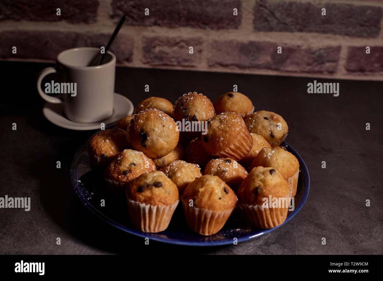 Gruppe von Muffins mit Schokolade auf blauem Teller weiter zu einer Tasse Milch Stockfoto