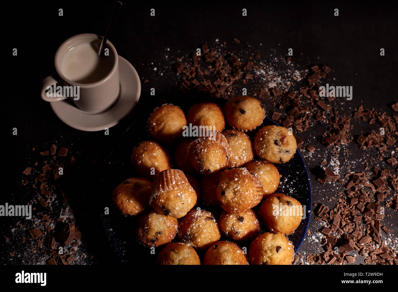 Gruppe von Muffins mit Schokolade auf blauem Teller weiter zu einer Tasse Milch Stockfoto