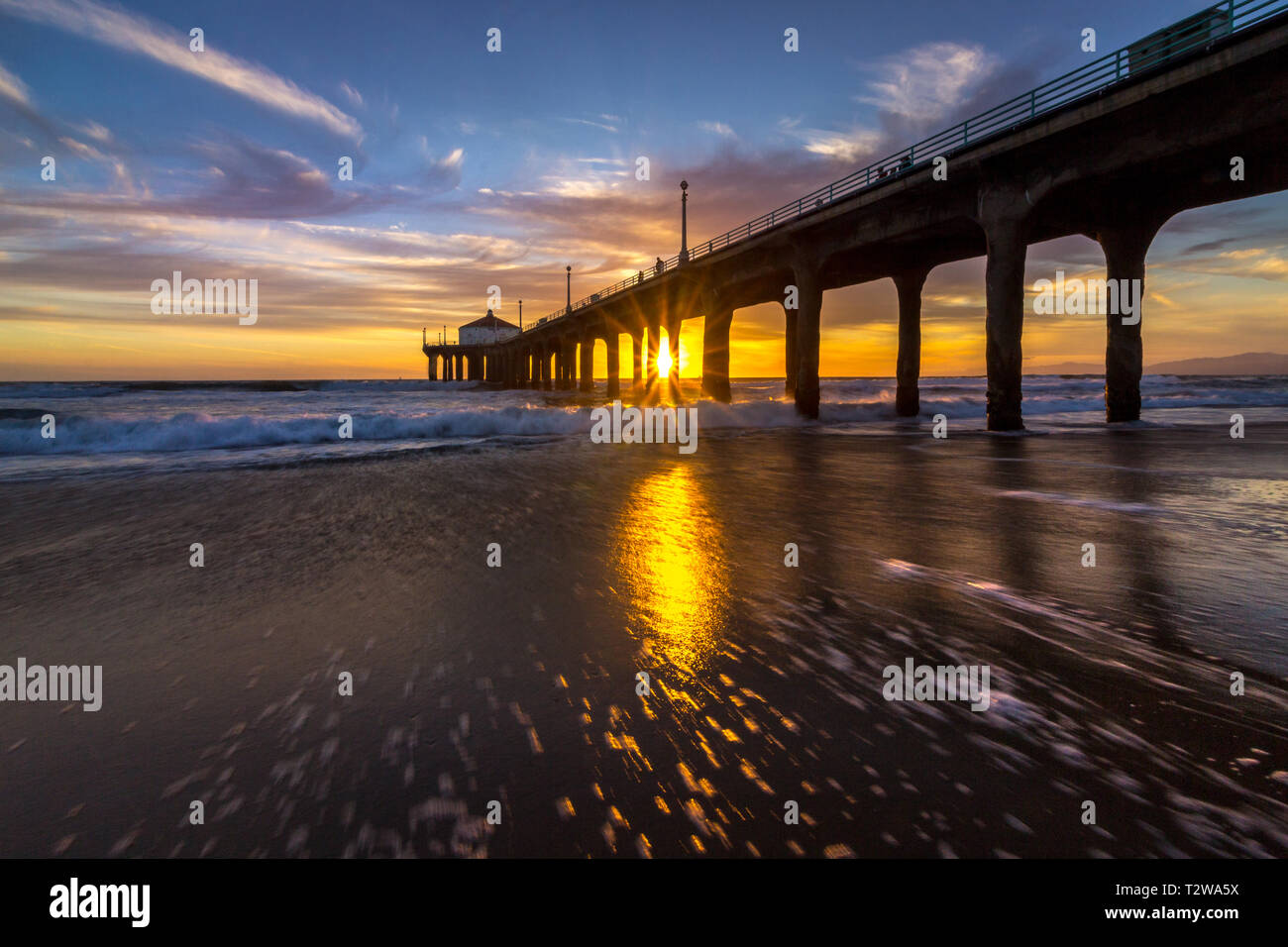 Lange Belichtung geschossen von bunten Himmel und Wolken über Manhattan Beach Pier bei Sonnenuntergang mit sanften Wellen auf dem Beach, Manhattan Beach, Californi Stockfoto
