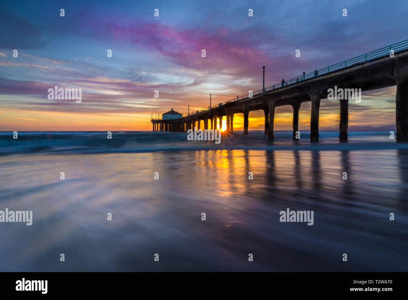 Lange Belichtung geschossen von bunten Himmel und Wolken über Manhattan Beach Pier bei Sonnenuntergang mit sanften Wellen auf dem Beach, Manhattan Beach, Californi Stockfoto