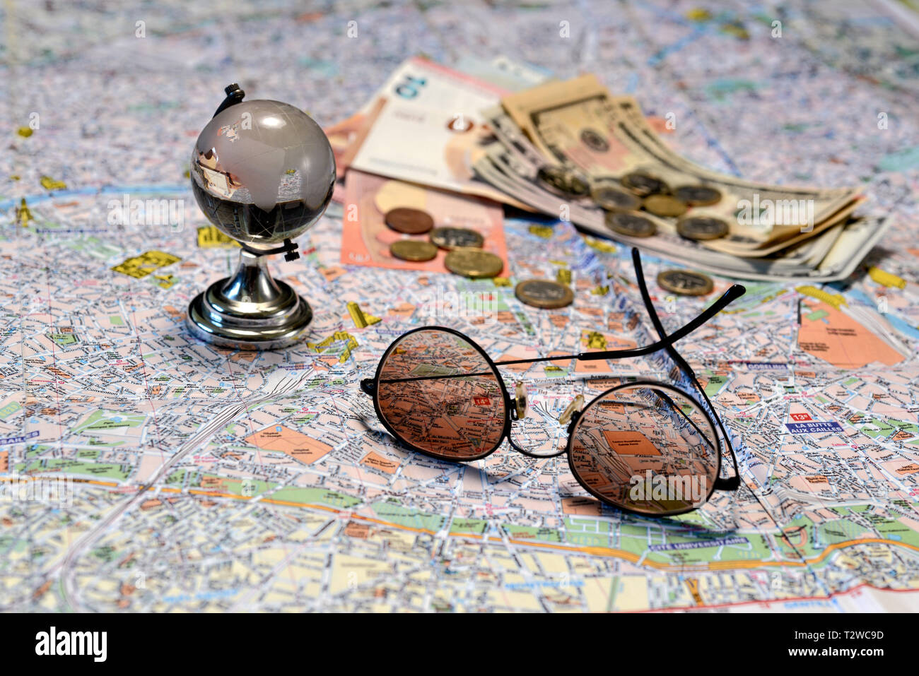 Sonnenbrille, ein glas kugel und Geld auf eine touristische Karte Hintergrund. Tourismus Konzept. Stockfoto