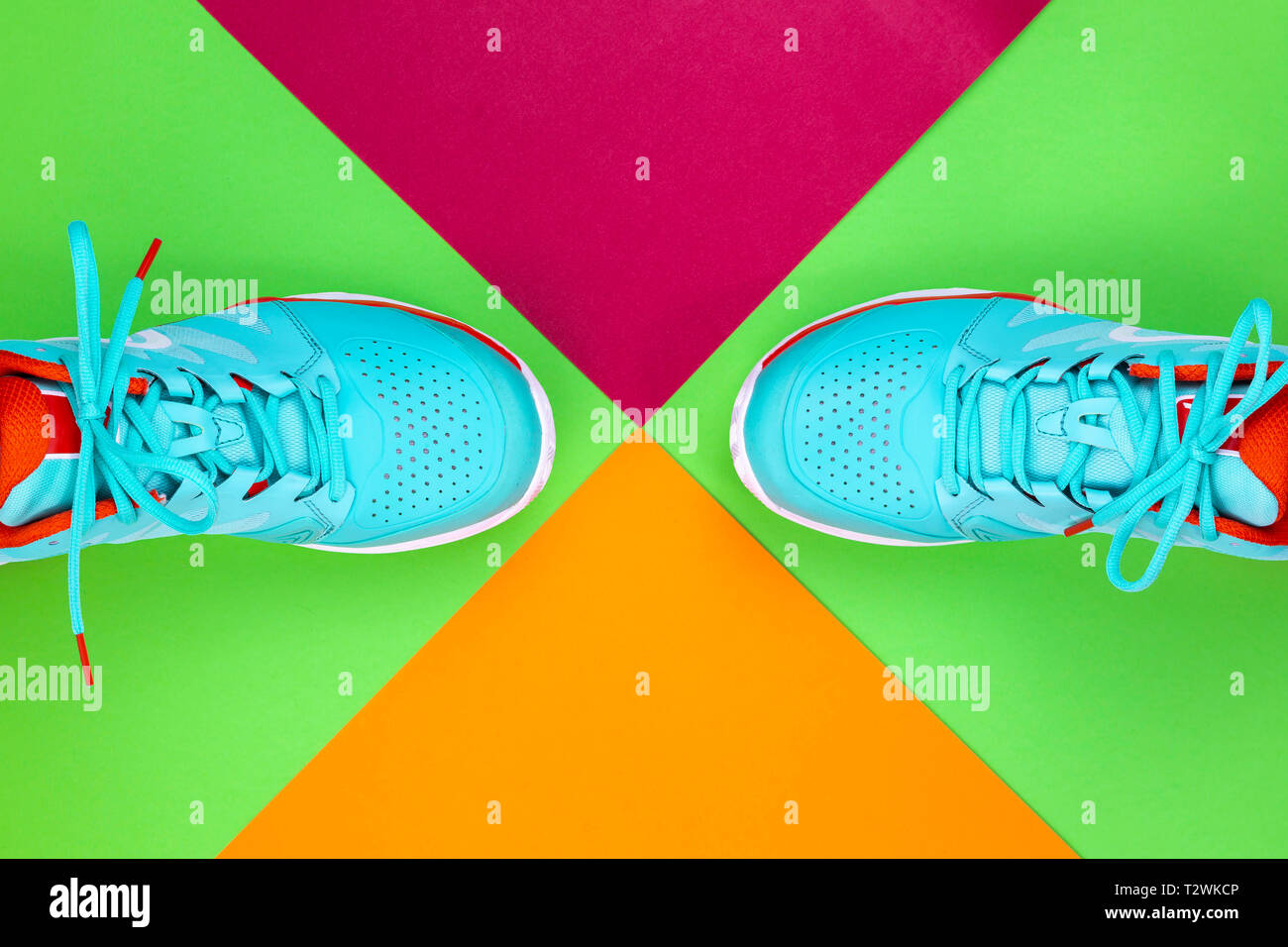 Rot, hellblau, weiß, Paar neue Tennisschuhe im Studio Schuß über Grün, Pink, Lila, Hintergrund. Direkt von oben. Stockfoto
