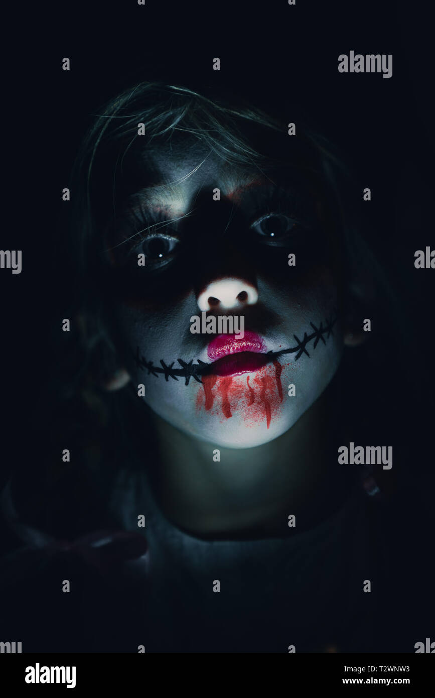 Porträt eines Kindes gekleidet wie ein horror Puppe mit Halloween. Beängstigend, Make-up, durch die Verwendung eines einzigen Licht Stockfoto