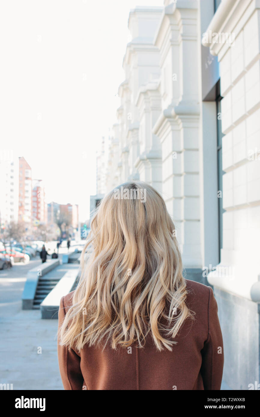 Elegante modische Frau mit Mantel mit dem Lockigen, blonden Haaren auf der Straße Stockfoto
