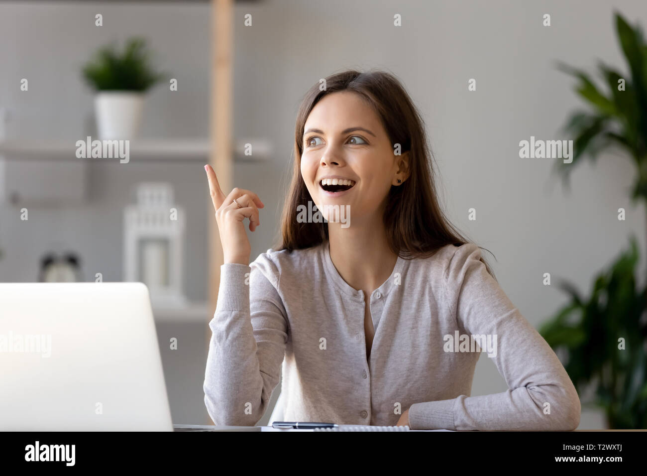 Junge Frau am Schreibtisch sitzen fühlt sich mit einer guten Idee begeistert Stockfoto