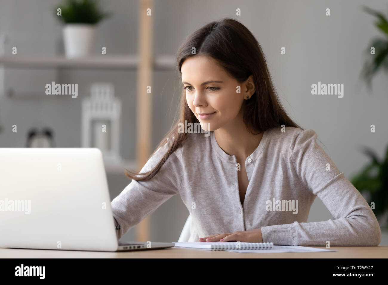 Frau sitzt am Schreibtisch sms Nachricht auf dem Computer fühlt sich gut Stockfoto