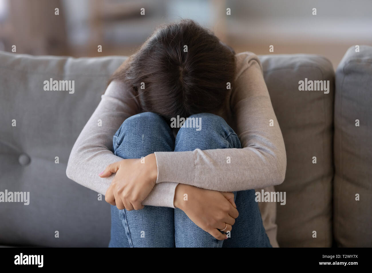 Deprimiert Frau sitzt auf der Couch Gefühl unglücklich alleine Schreien Stockfoto