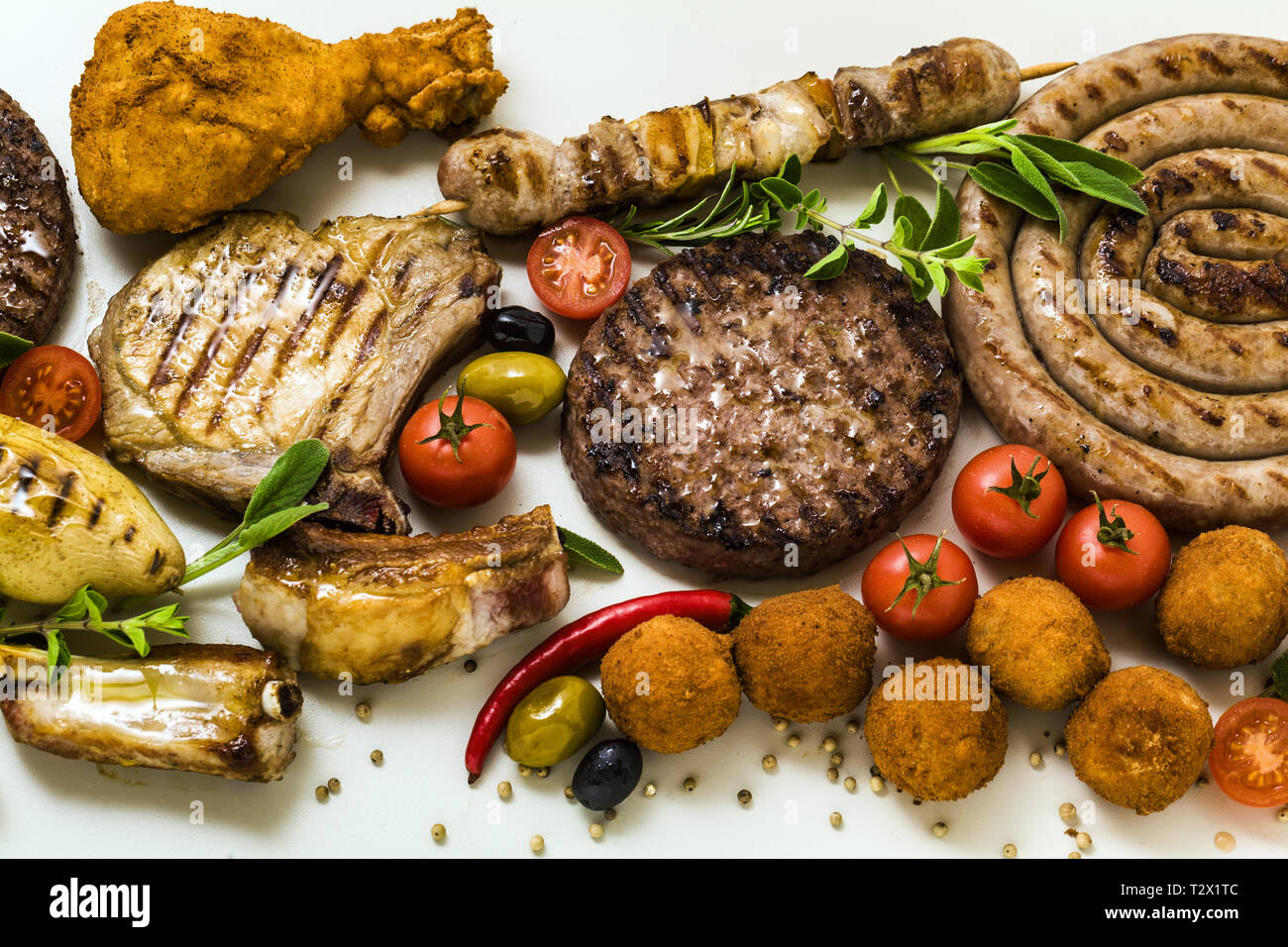 BBQ-Fleisch Party mit verschiedenen Arten von Fleisch: Rindfleisch Burger,  Schweinerippchen, Türkei Frikadellen, Hähnchen Schenkel paniert mit  Kartoffeln und Tomaten, Gewürze und Stockfotografie - Alamy