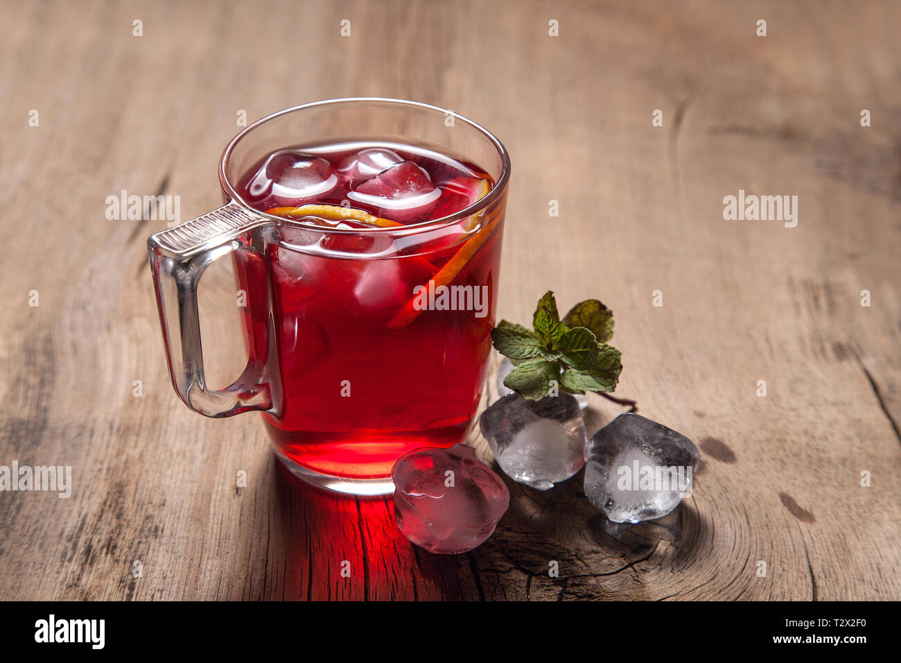 Sommer iced Drink - hibiskus kalten Tee mit Eis und Minze. Tasse Hibiscus kalten Tee mit Eis, Zitrone und Minze auf vintage Holz- Hintergrund Stockfoto