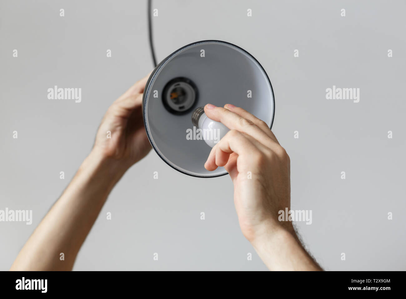 Ändern der Glühbirne für LED-Lampe in Stehleuchte in der Farbe schwarz. Auf hellgrauem Hintergrund. Stockfoto