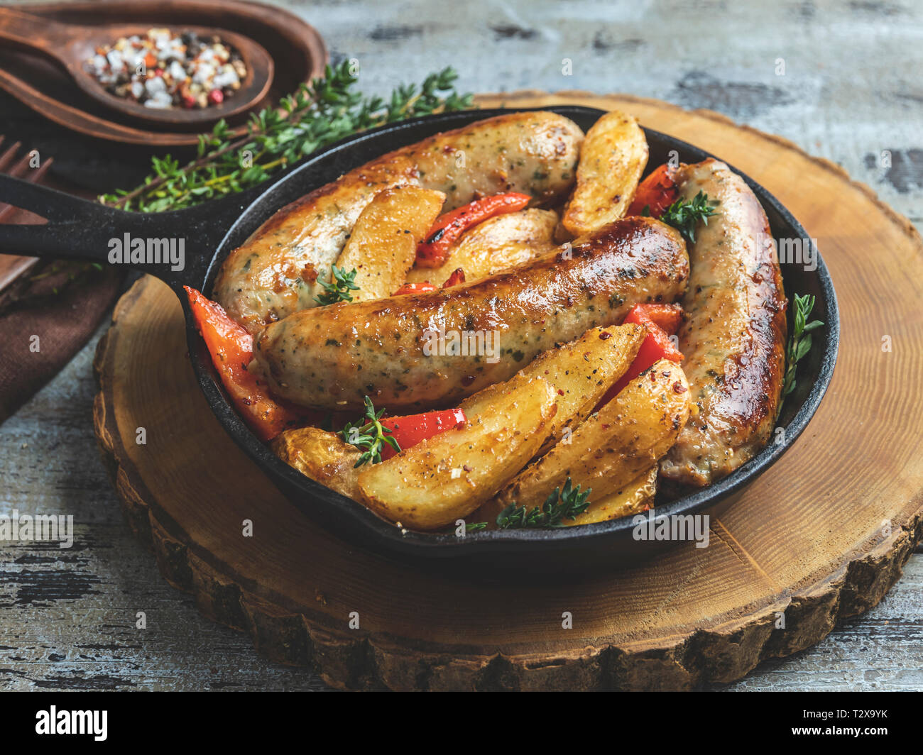 Gegrilltes Hühnchen Würstchen mit gebratenen Kartoffeln und Paprika in eine eiserne Pfanne Stockfoto