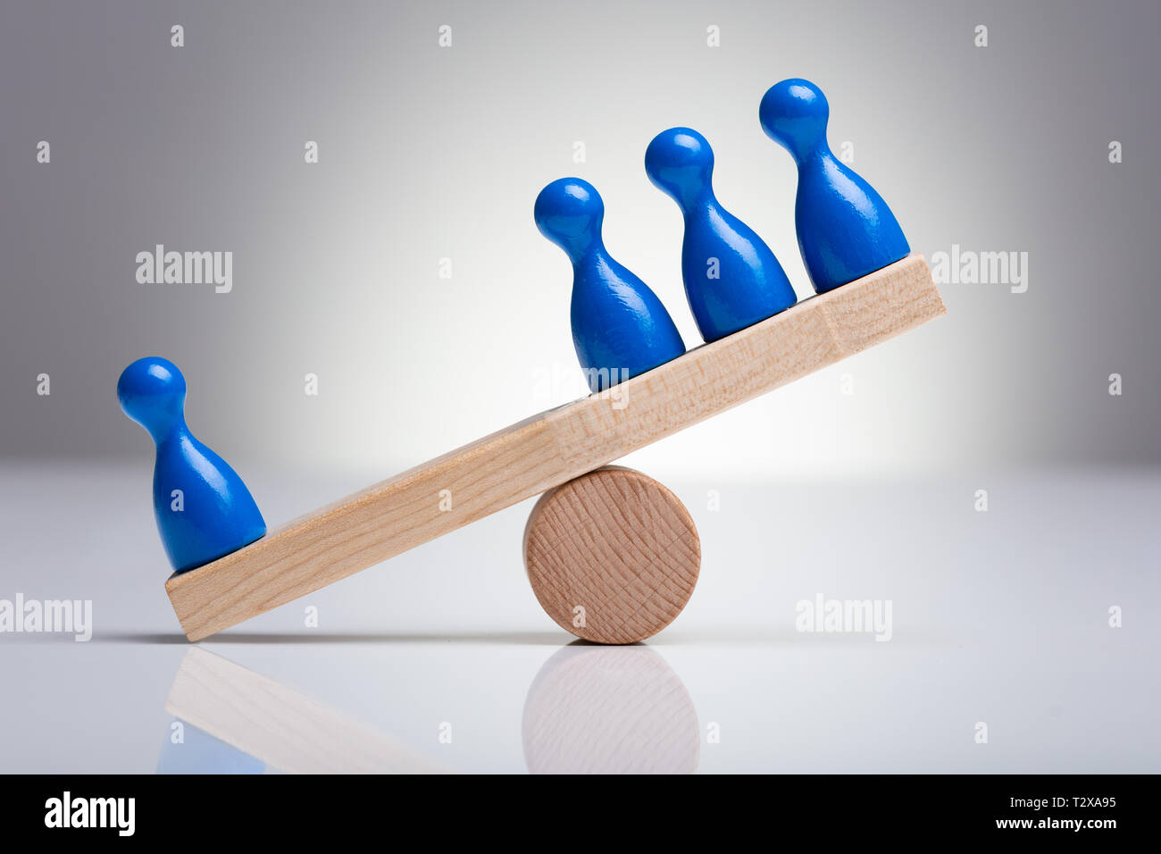 Blaue Spielfiguren Figuren Balancieren auf Holz- Wippe über den Schreibtisch Stockfoto