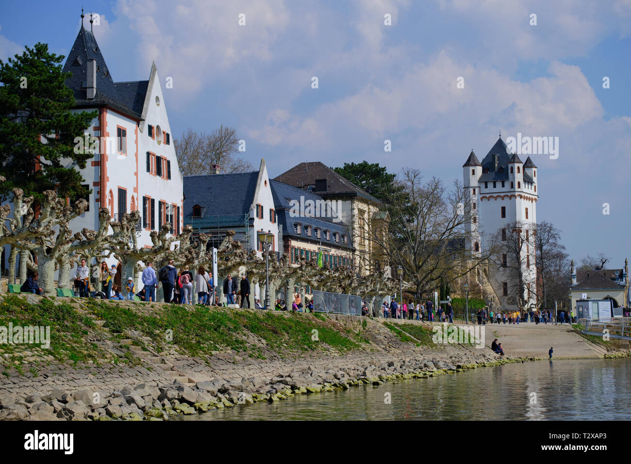Eltville, Deutschland - 31. März 2019: River Promenade in Eltville mit Menschen an einem sonnigen Tag mit Blick auf das Schloss. Stockfoto