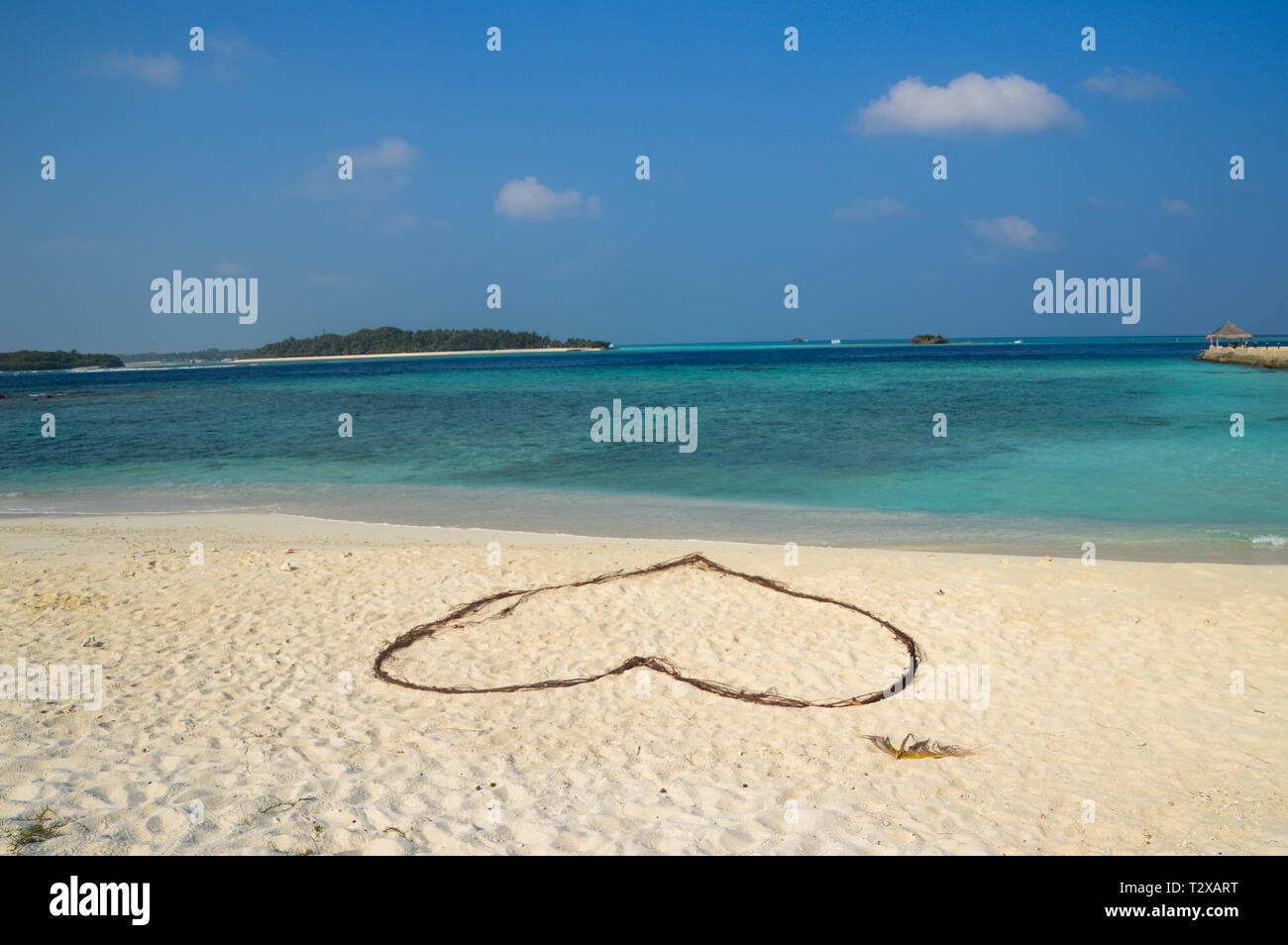 Romantische Herz auf Sand an einem tropischen Strand. Klare türkisfarbene Meer. Malediven Inseln. Stockfoto