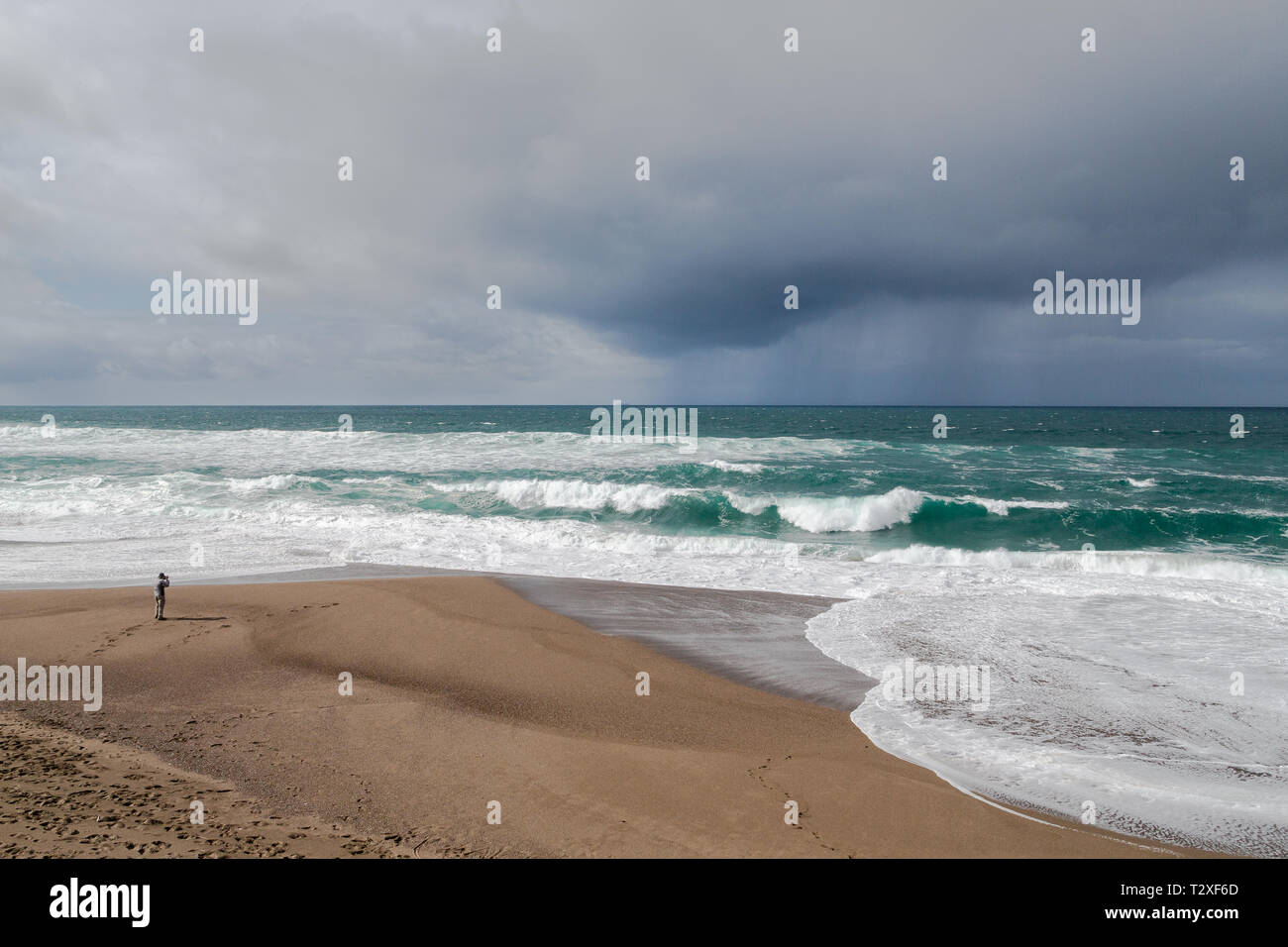 Ein Fotograf sieht klein im Vergleich zu den stürmischen Meer und tristen Regen Wolken an der nördlichen Küste von Kalifornien. Stockfoto