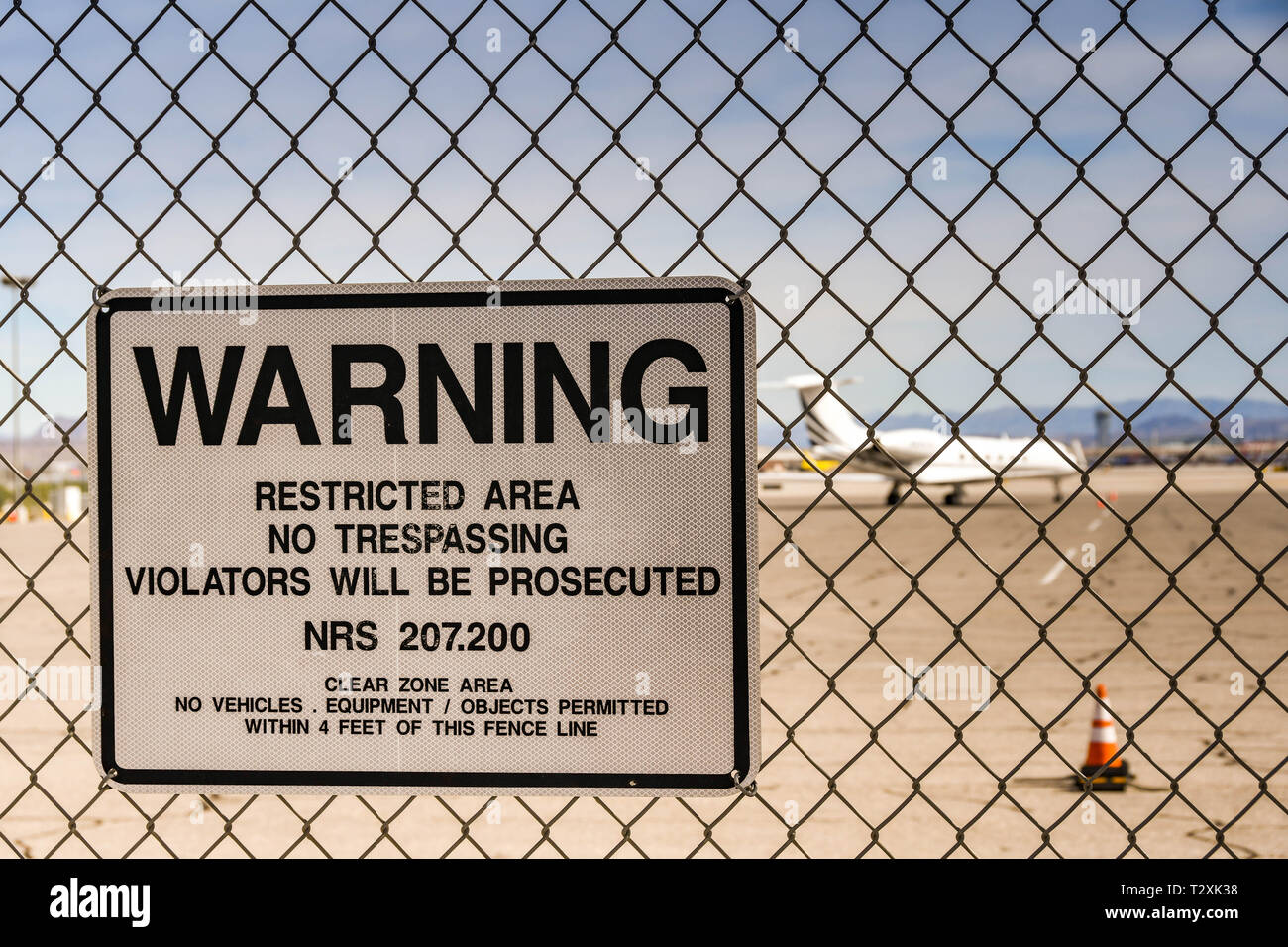 LAS VEGAS, Nevada, USA - Februar 2019: Warnschild an einen Zaun um den internationalen Flughafen McCarran. Im Hintergrund ist eine private Executive Jet. Stockfoto