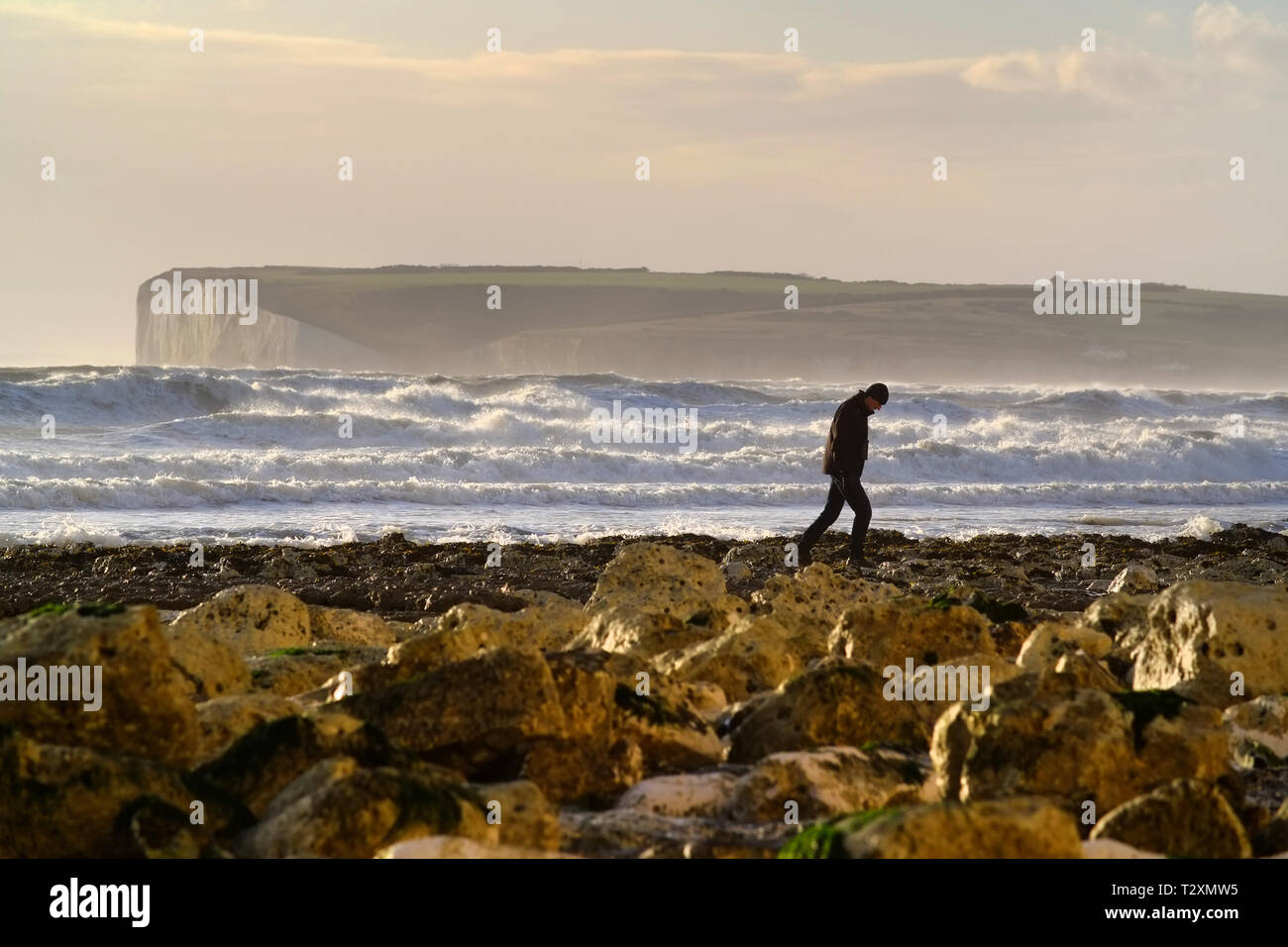 Person zu Fuß auf einem Strand in Sussex bei Sonnenuntergang. Stockfoto