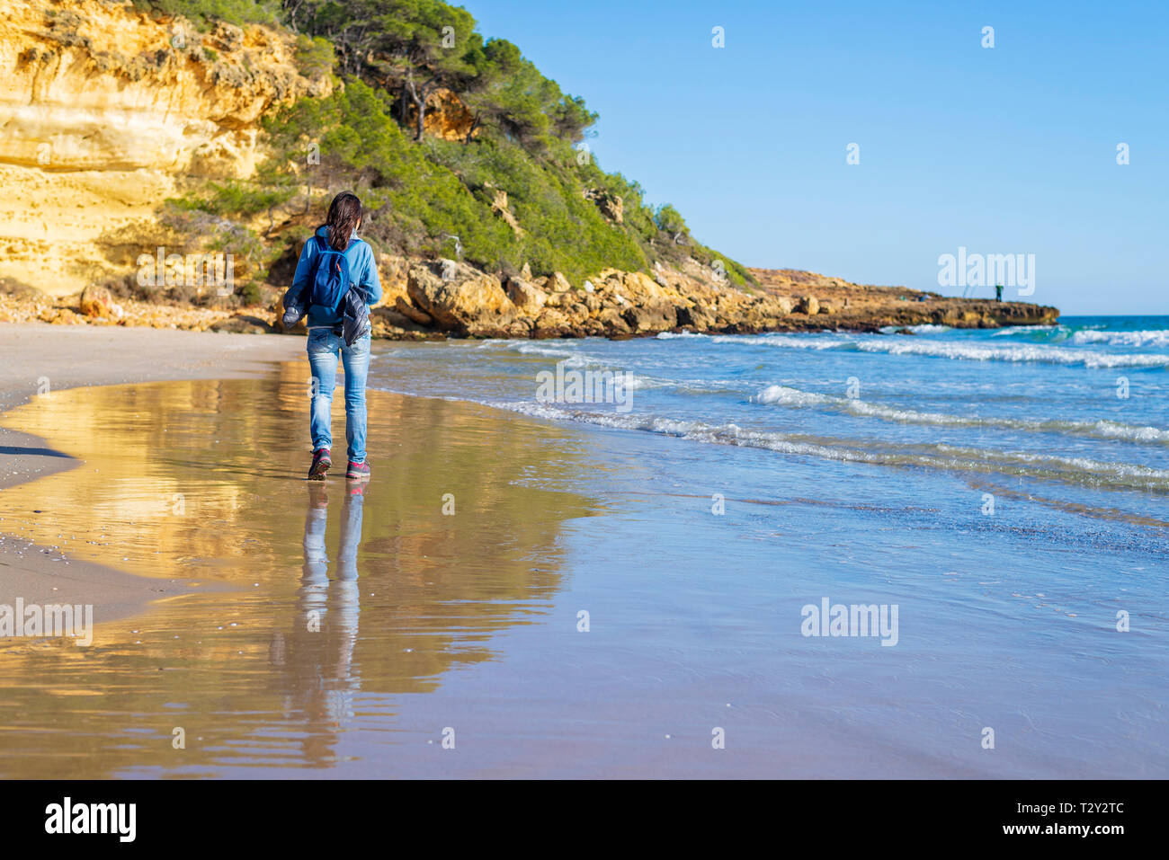 Zurück Blick auf junge Frau mit Rucksack zu Fuß am Strand Stockfoto