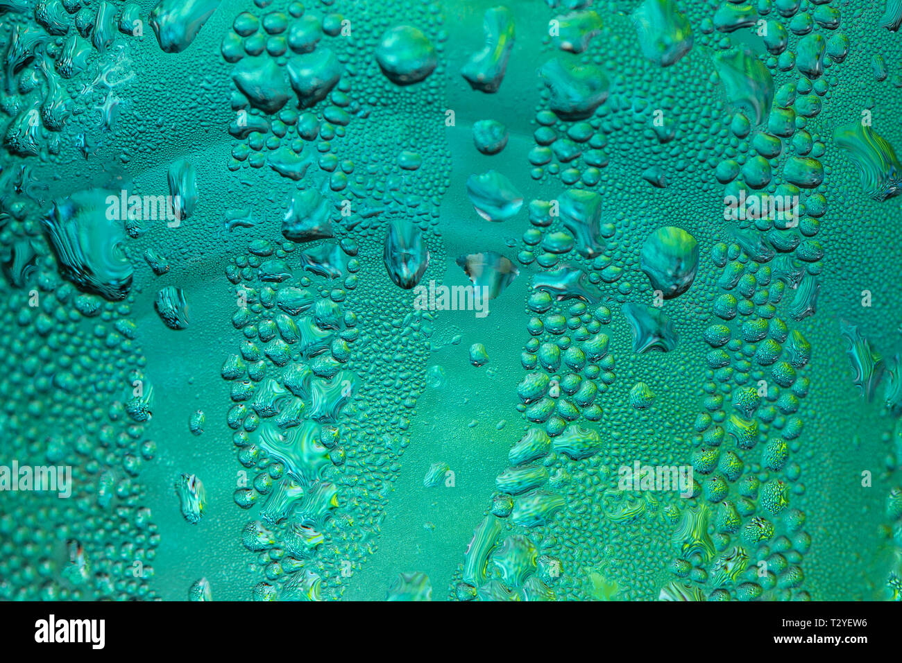 Random Wassertropfen auf der Oberfläche aus Glas mit grünem Licht Hintergrund Stockfoto