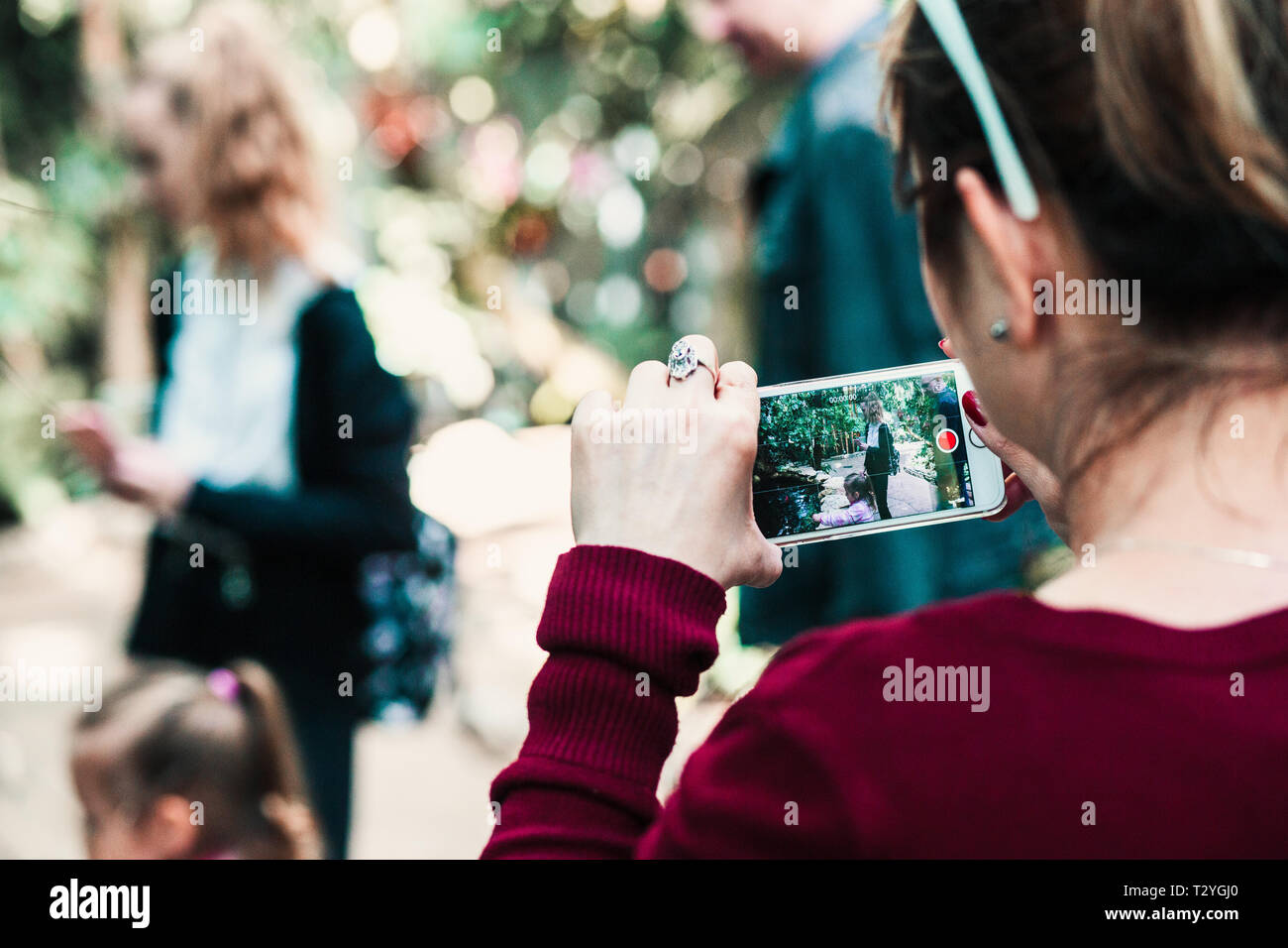 Junge Frau mit Smartphone, am Telefon Bildschirm schaut, ist die Aufnahme einer Familie Reise Stockfoto