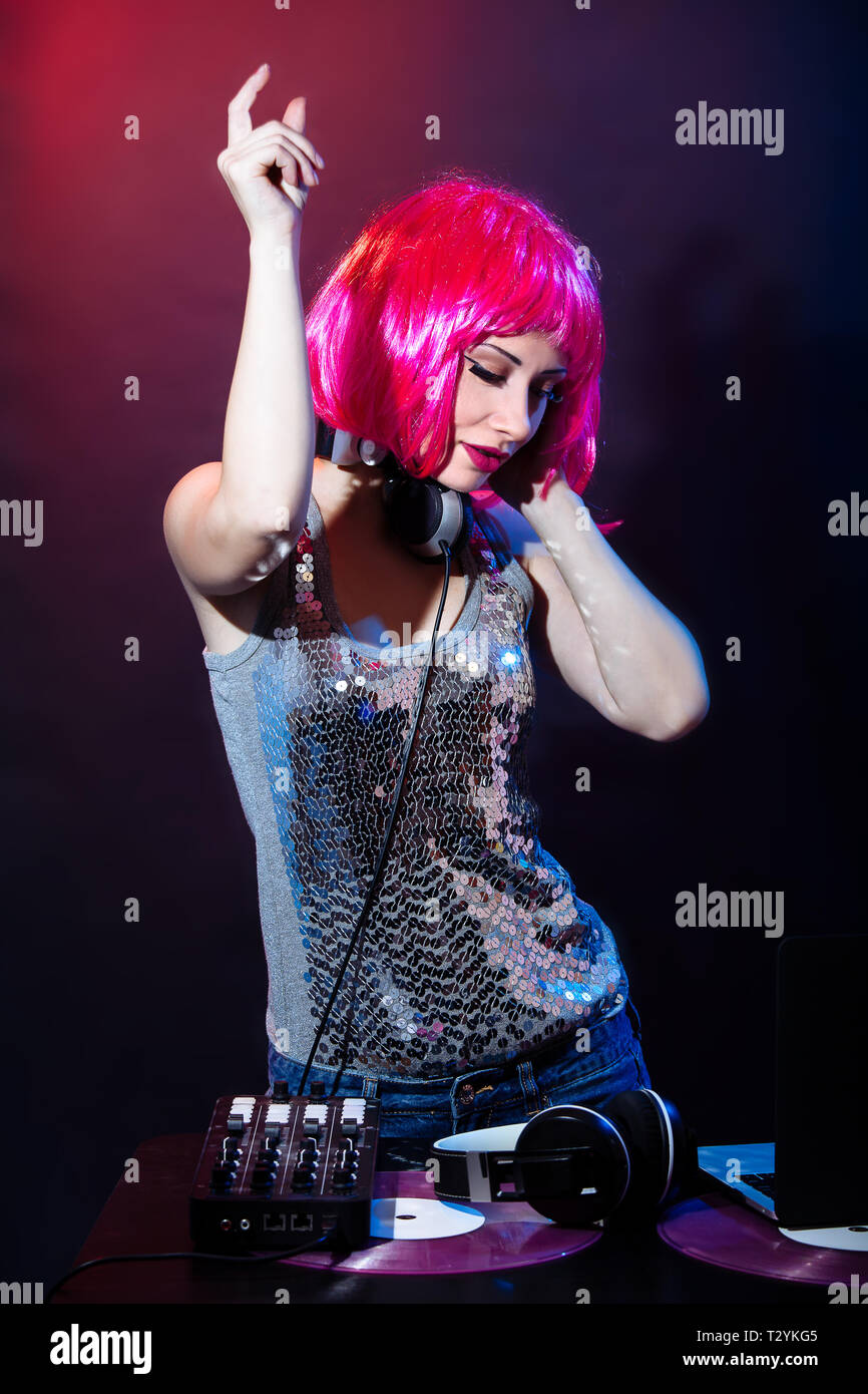Porträt einer jungen Frau mit rosa Haaren und vintage Brille auf roten und blauen Hintergrund. DJ-Frau mit headphne und rosa Vinyls spielt Musik Disko. Gla Stockfoto