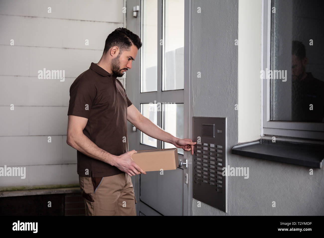 Seitenansicht der Mann mit Karton Drücken Sie die Taste Intercom Home Eintragen Stockfoto