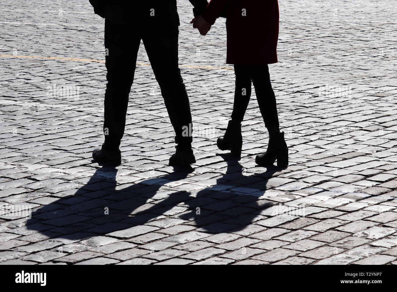 Silhouette der Liebe Paar auf der Straße. Zwei Menschen zu Fuß und halten sich an den Händen, Schatten auf Bürgersteig, Konzept für die romantische Liebe, Familie, Beziehungen Stockfoto