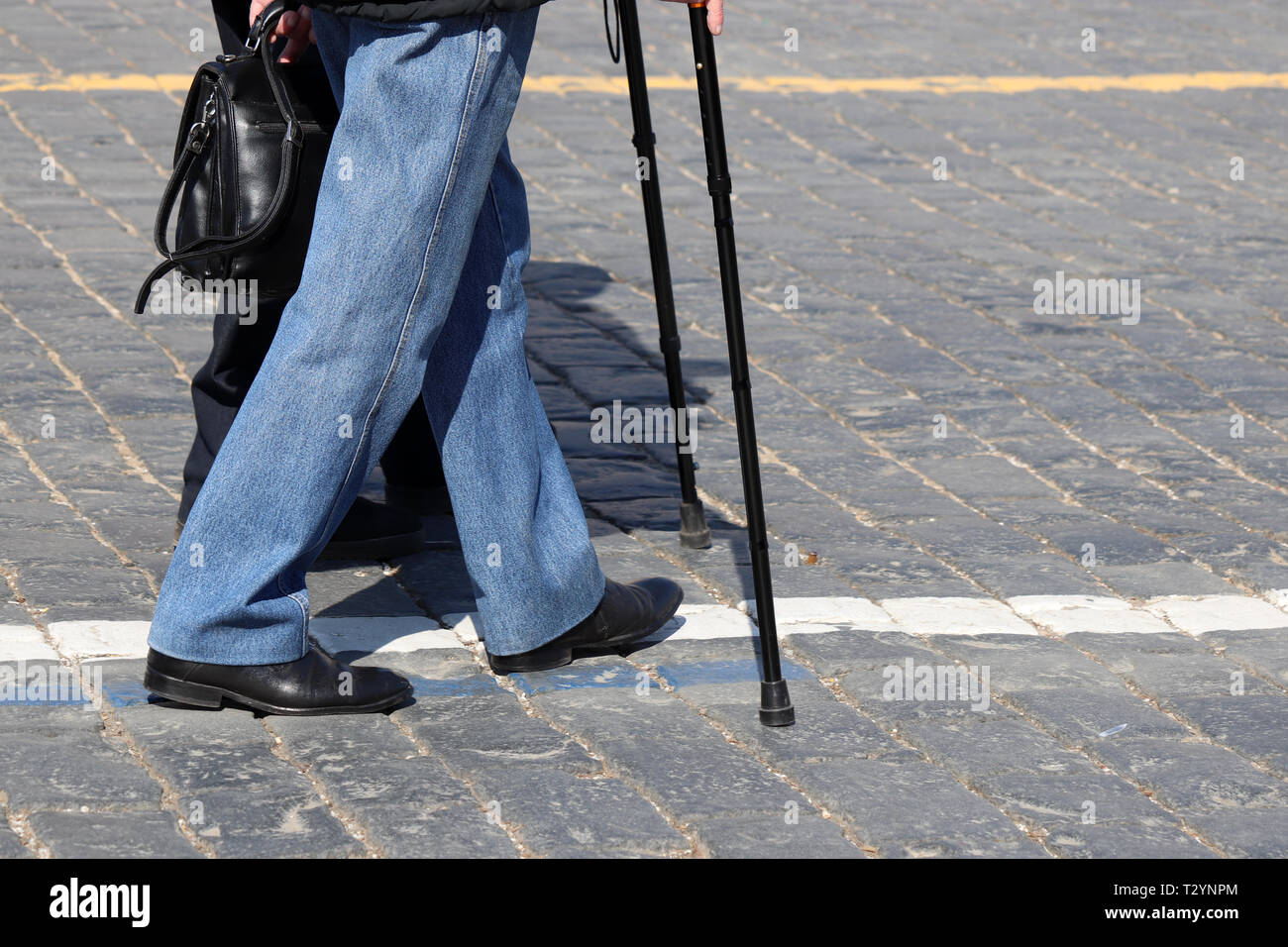 Die Leute gehen mit Stock auf die Straße. Zwei Männer auf dem Bürgersteig, Konzept für Erwerbsunfähigkeit, Alter, humpelnde Person Stockfoto