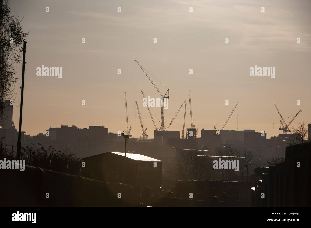 Baukräne in der Hitze Dunst gegen die Sheffield City Skyline Silhouette Stockfoto