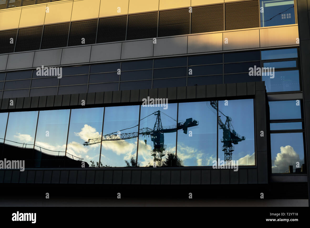 Reflexionen von baukränen in einer Stadt Büro schwarzes Fenster in der Abenddämmerung Stockfoto