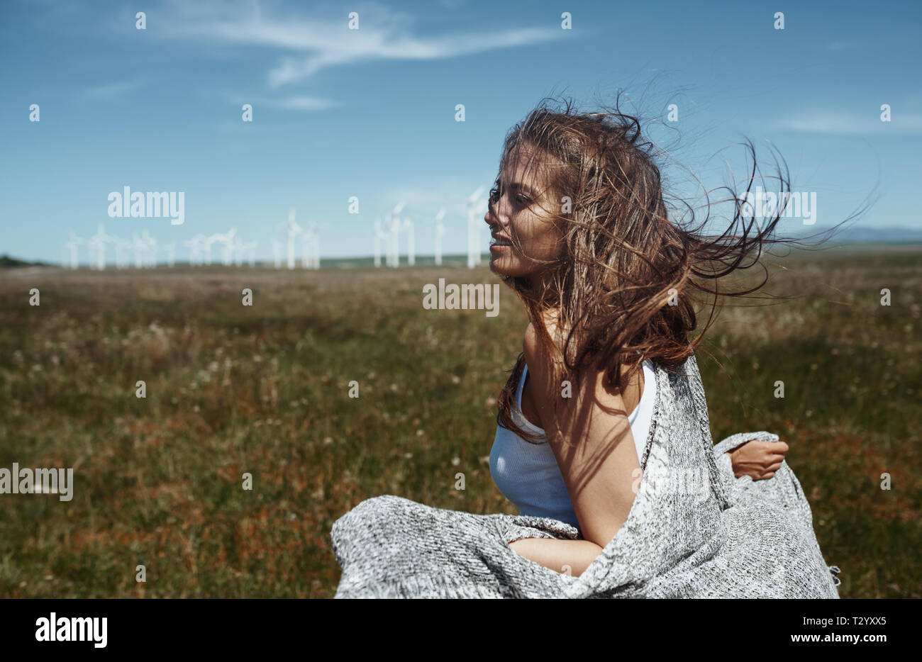 Frau mit langen zerzausten Haaren neben dem Wind Turbine mit dem Wind, Stockfoto