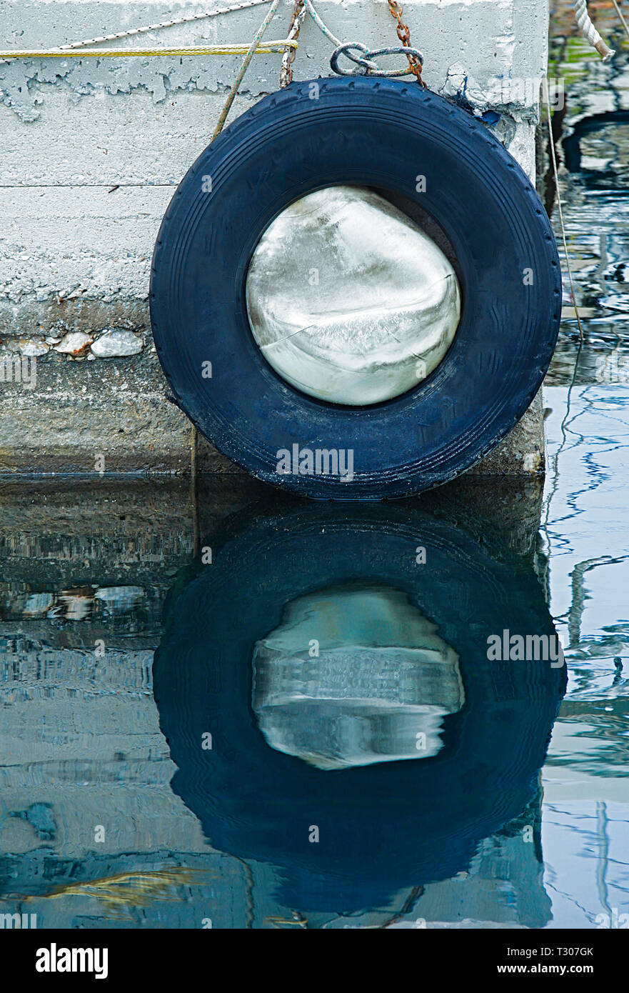 Wand Guard für Dock Stoßfänger auf Marina Wand mit Reflexion an der Oberfläche des Wassers. Stock Bild. Stockfoto