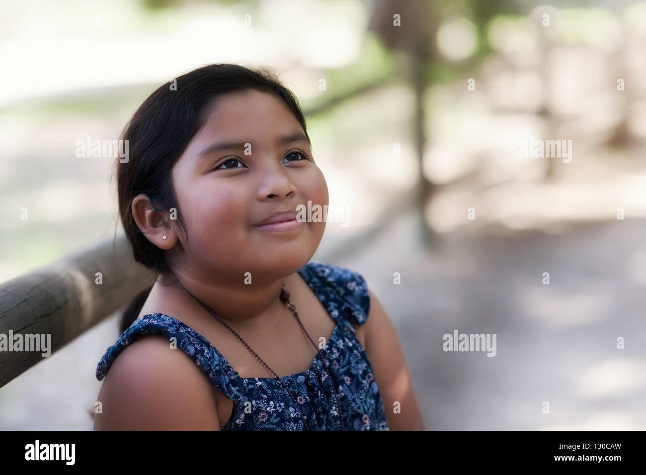 Süße 8 jährige Mädchen gemischter ethnischer Zugehörigkeit, starrte in den Himmel mit einem nachdenklichen Blick und in traditionellen Country Western gekleidet. Stockfoto
