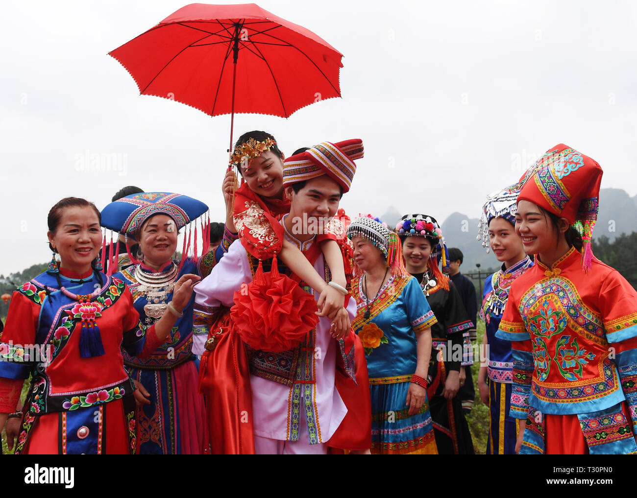 Du'an, China Guangxi Zhuang autonomen Region. 4 Apr, 2019. Ein "Bräutigam" hat die "Braut" auf seinem Rücken während einer Leistung der Hochzeit brauch der Zhuang ethnische Gruppe in Du' ein Yao autonomen County, South China Guangxi Zhuang autonomen Region, 4. April 2019. Credit: Lu Boan/Xinhua/Alamy leben Nachrichten Stockfoto