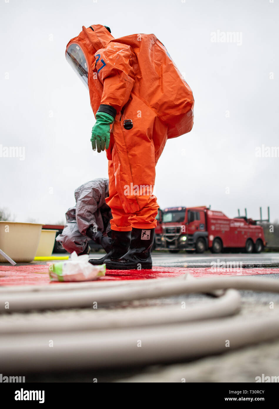 Bielefeld, Deutschland. 05 Apr, 2019. Ein Feuerwehrmann in einem NBC Anzug steht noch an der Unfallstelle. Aufgrund eines LKW-Unfall, der Polizei blockierten die A2 in Richtung Hannover Am Autobahnkreuz Bielefeld früh am Freitag morgen. Ein Polizeisprecher sagte am Freitag, dass Anhänger des Lkw, auf seine Seite gekippt, derzeit drohte eine Boeschung zu fallen. Credit: Guido Kirchner/dpa/Alamy leben Nachrichten Stockfoto