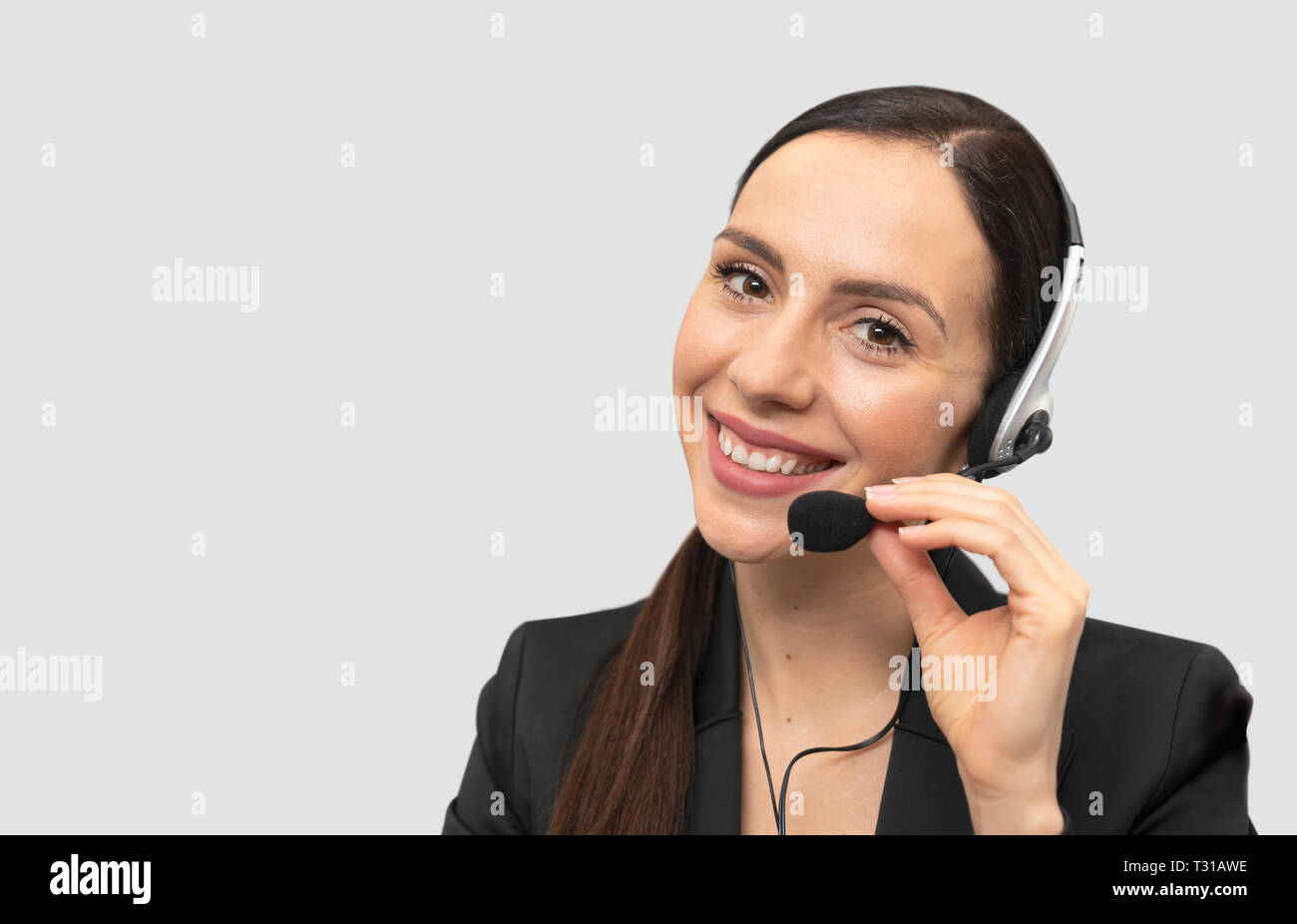 Berater von Call Center in Kopfhörer auf grauem Hintergrund. Helpline Operator mit Headset Stockfoto