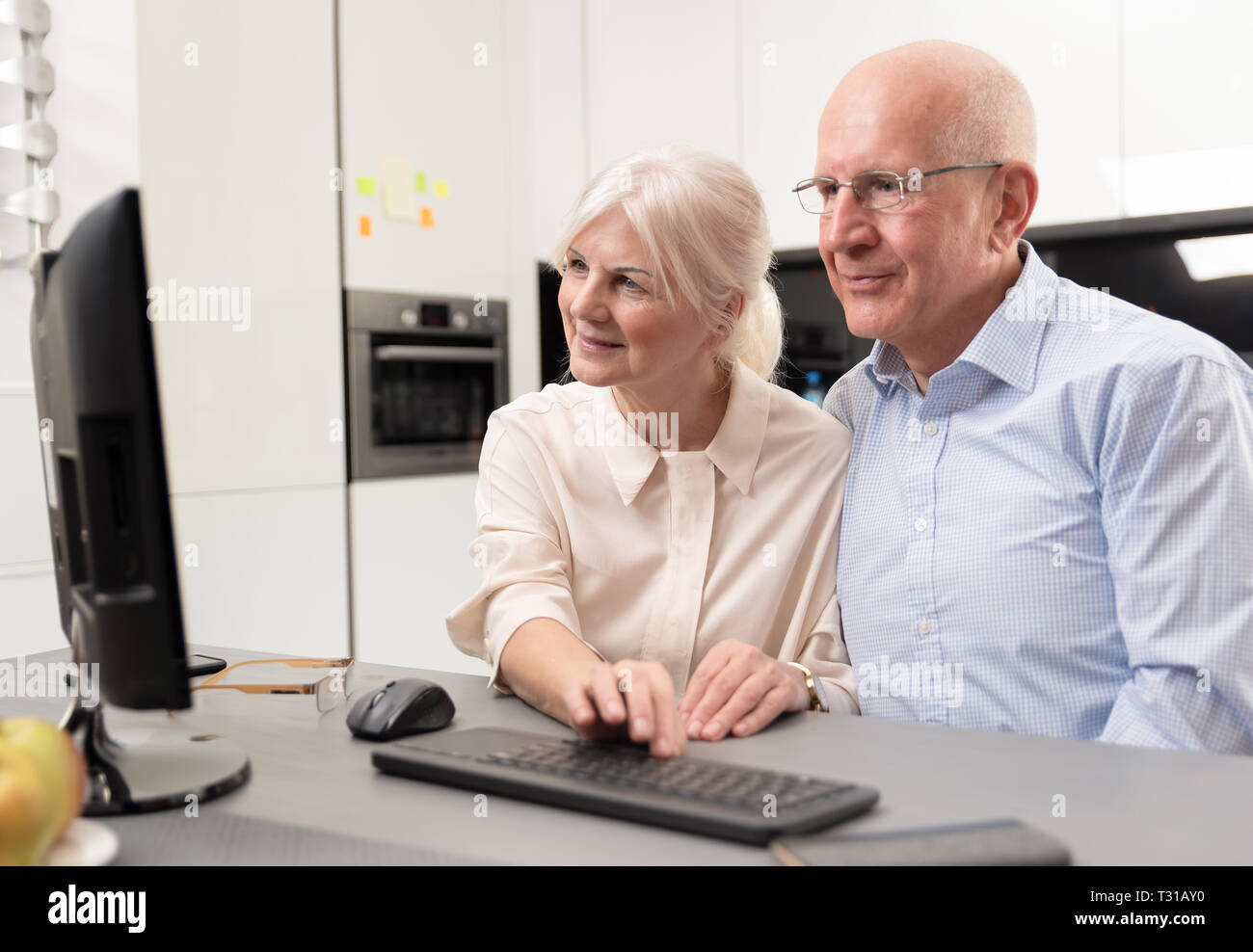 Gerne ältere Paare zusammen am Computer genießen. Senioren einen Computer benutzen, betrachten Sie die Bilder, die Sie erhalten haben. Stockfoto