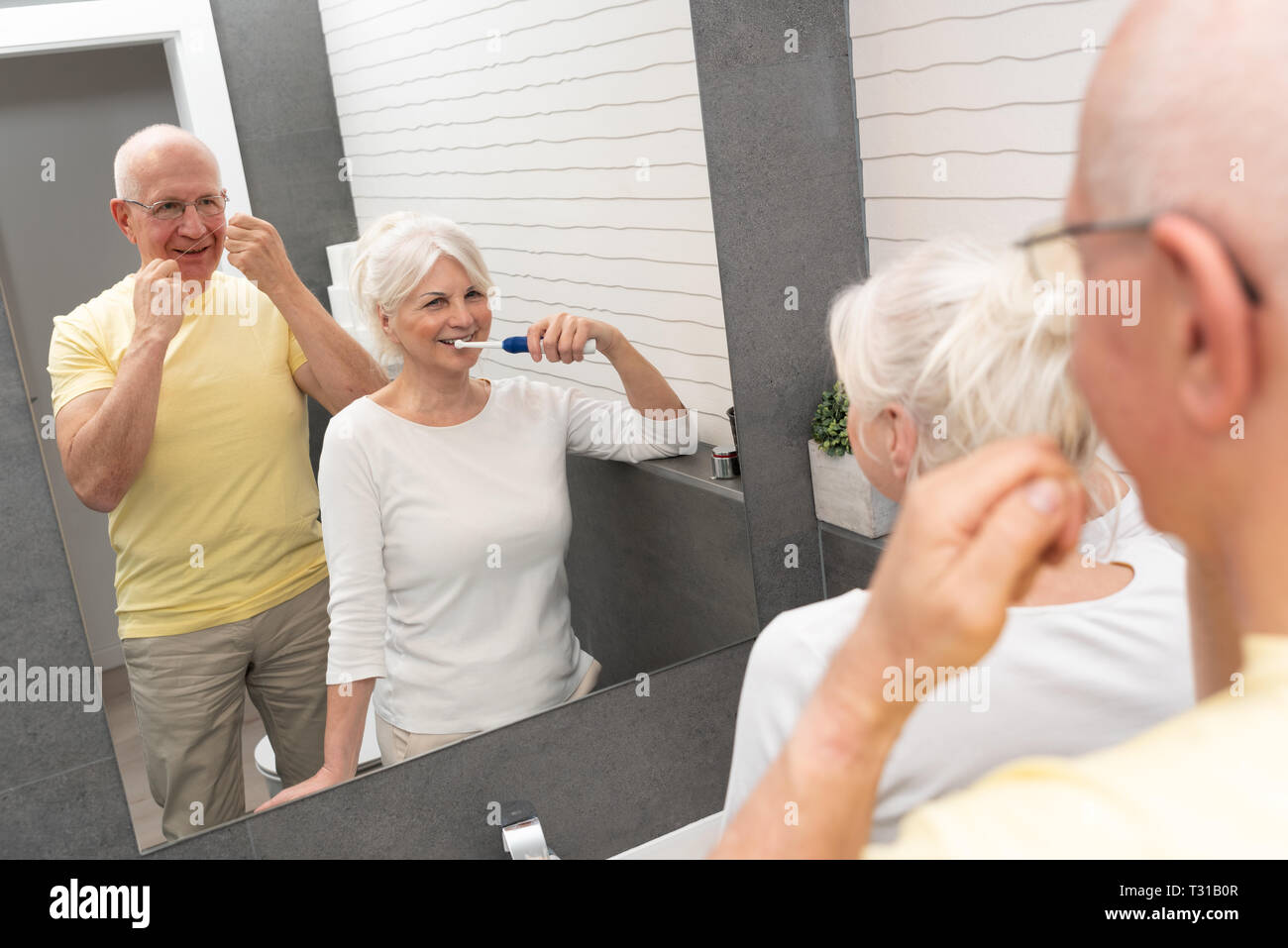 Ältere Menschen mit Zähneputzen und Zahnseide. Morgen im Badezimmer Stockfoto