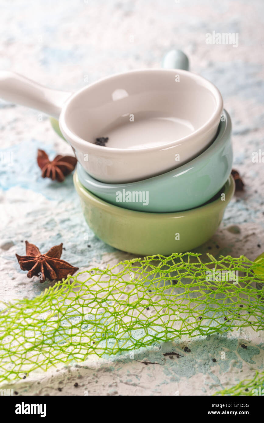 Vertikale Foto von drei kleine Schüsseln oder Tassen. Cups sind einfach Halter. Jede Schale hat eine andere Farbe: Weiß, Blau und Grün. Gewürze sind rund um verschüttete Stockfoto